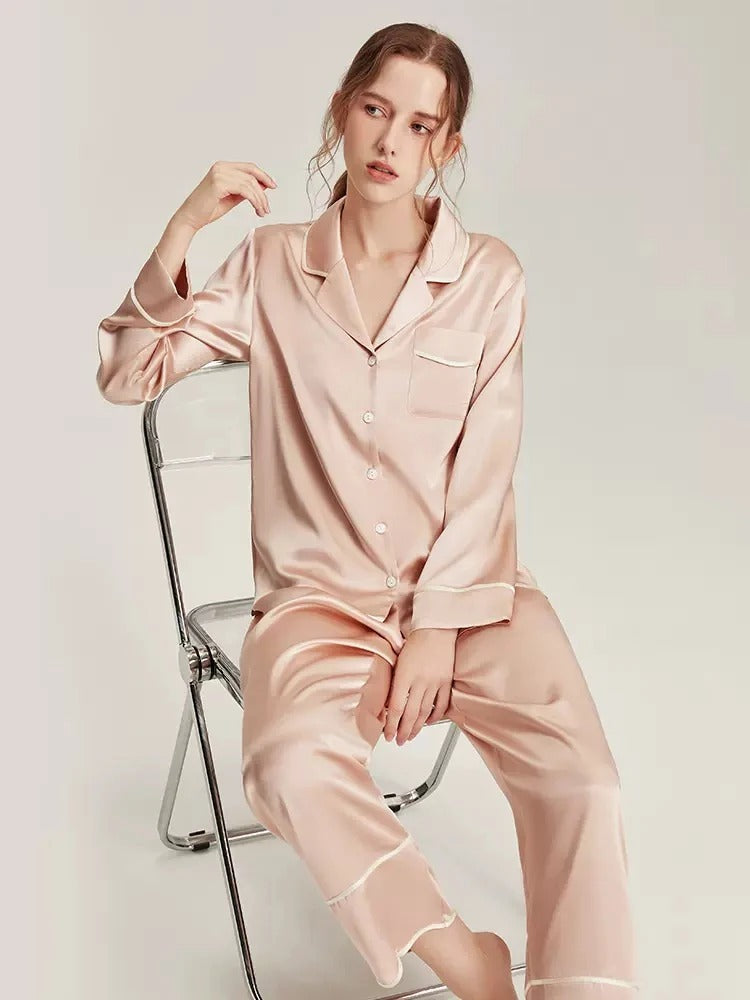 Donna seduta che indossa pigiama in seta rosa 100% Mulberry due pezzi con camicia e pantaloni Bella Seta