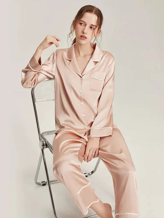 Donna seduta che indossa pigiama in seta rosa 100% Mulberry due pezzi con camicia e pantaloni Bella Seta